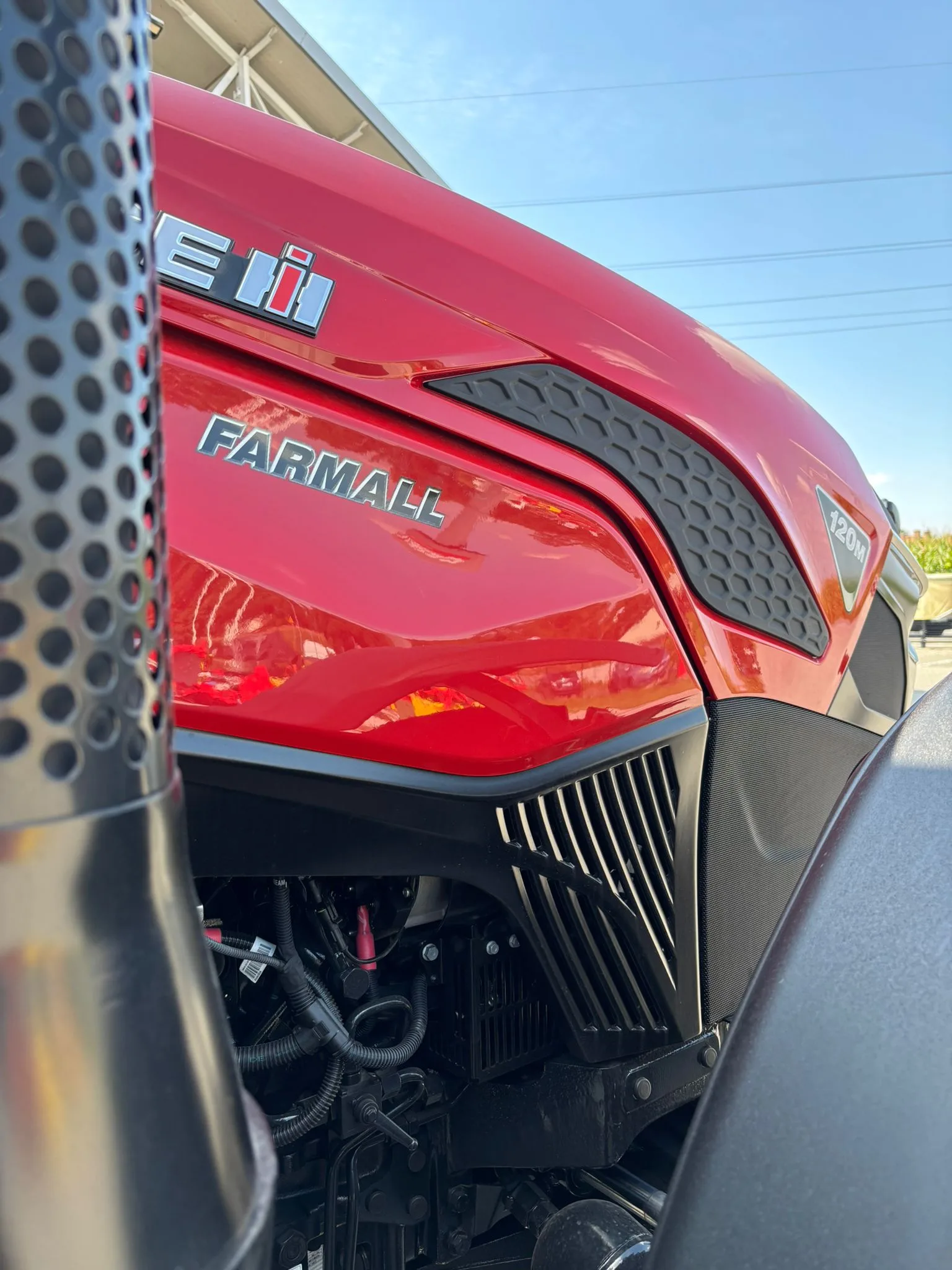 Zbliżenie logo CASE IH i napisu FARMALL na czerwonej masce ciągnika 120M